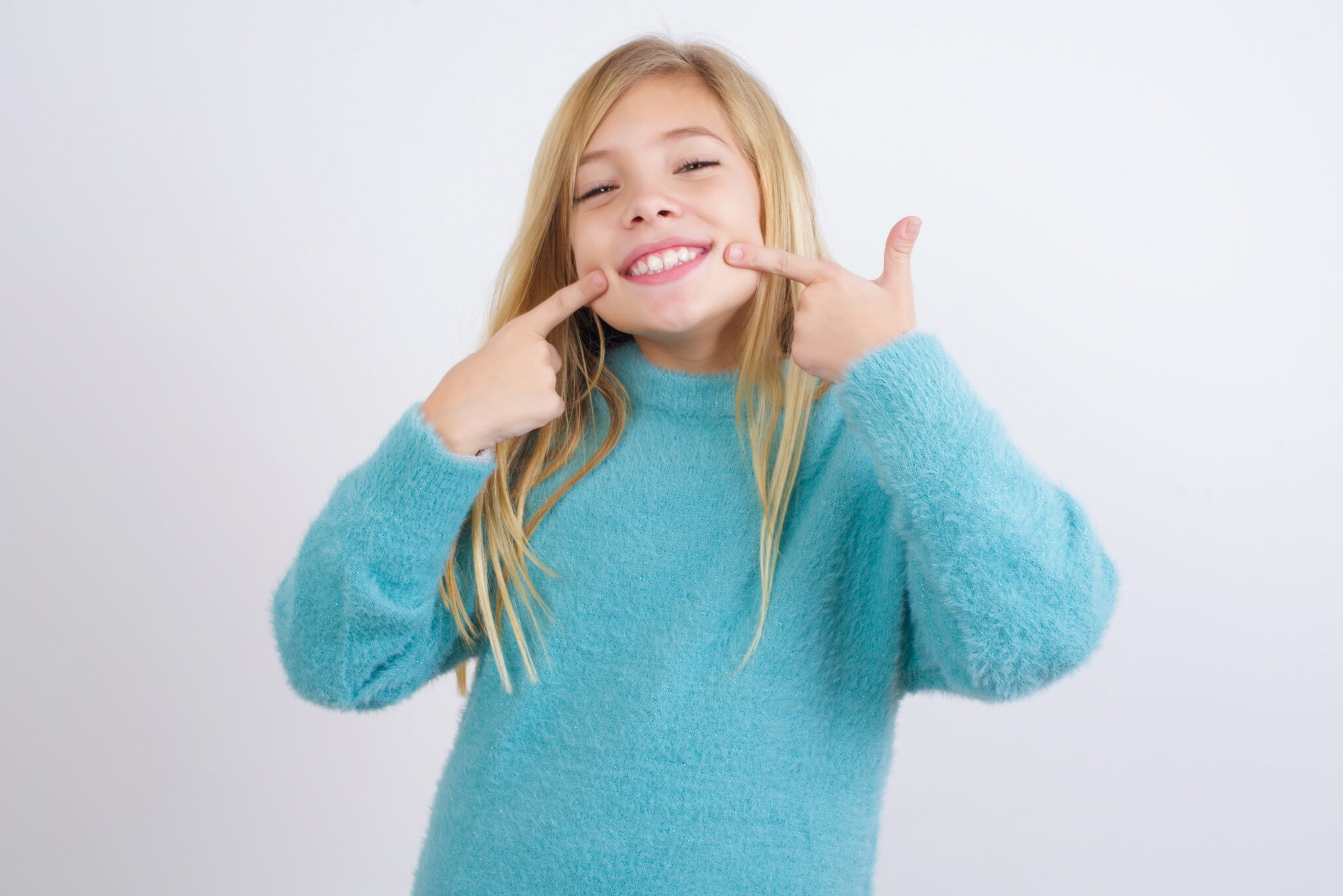 Child smiling and pointing to her teeth
